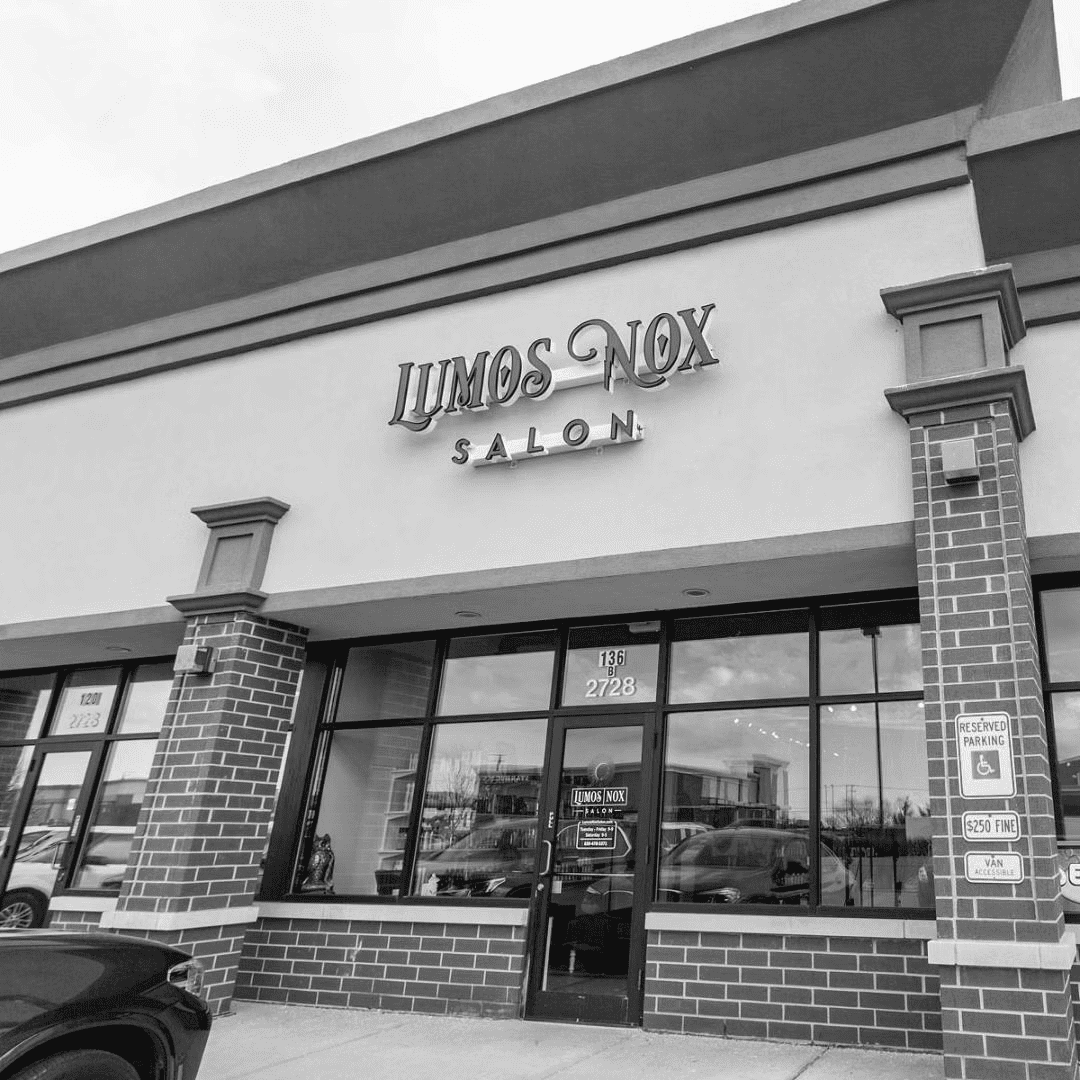 Exterior of Lumos Nox Salon with accessible parking sign and glass storefront.